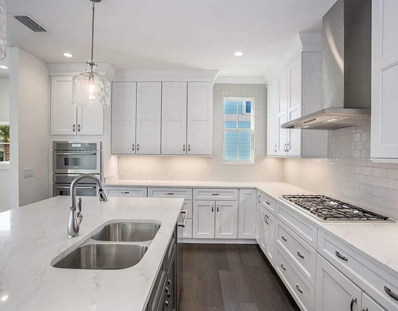 Bright modern kitchen with white cabinetry and a large island sink.
