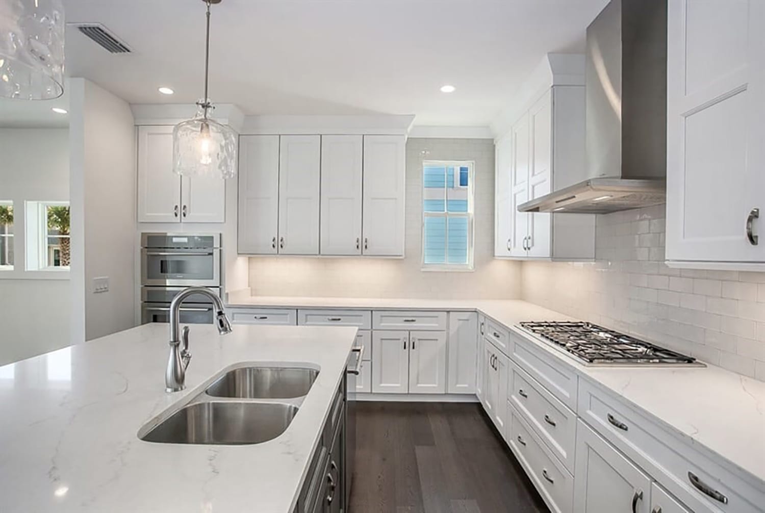 Bright modern kitchen with white cabinetry and a large island sink.
