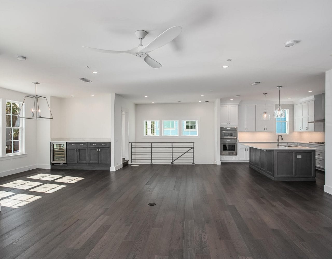 Spacious modern kitchen and living area with dark hardwood floors and ample lighting.