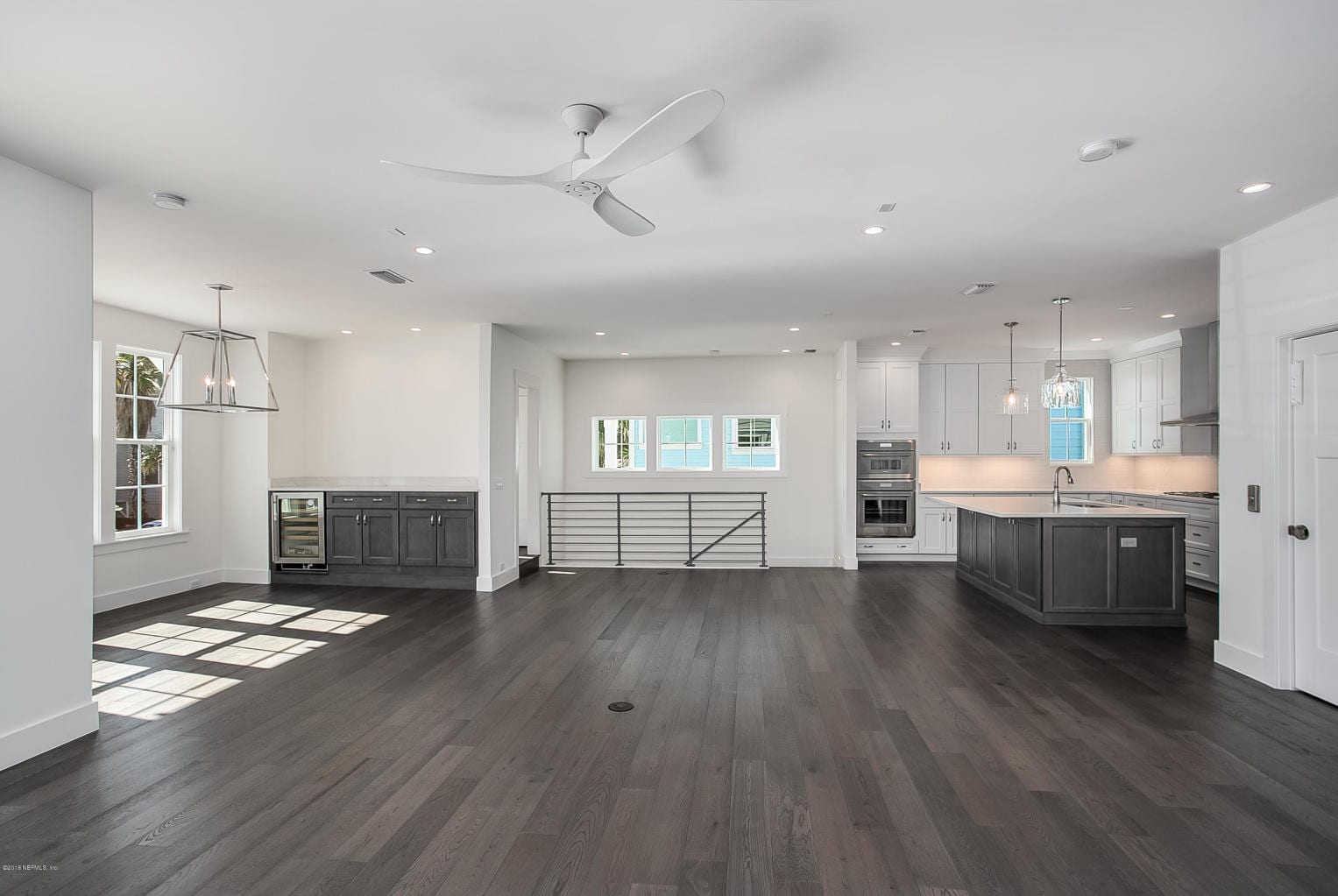 Spacious modern kitchen and living area with dark hardwood floors and ample lighting.