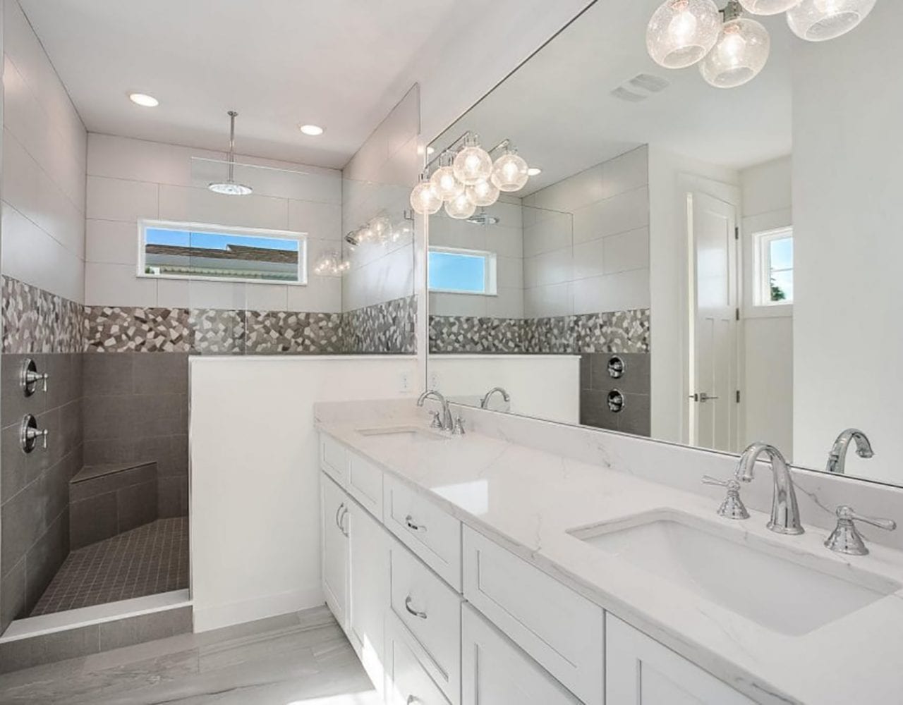 Bright, modern white bathroom with dual sinks and decorative lighting.