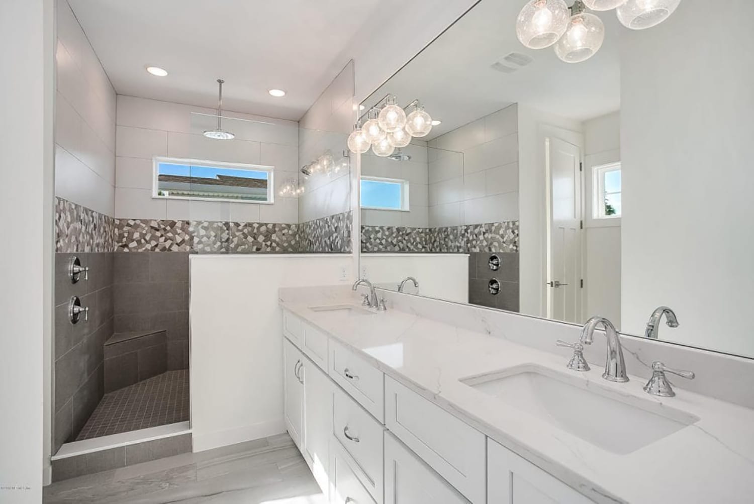 Bright, modern white bathroom with dual sinks and decorative lighting.