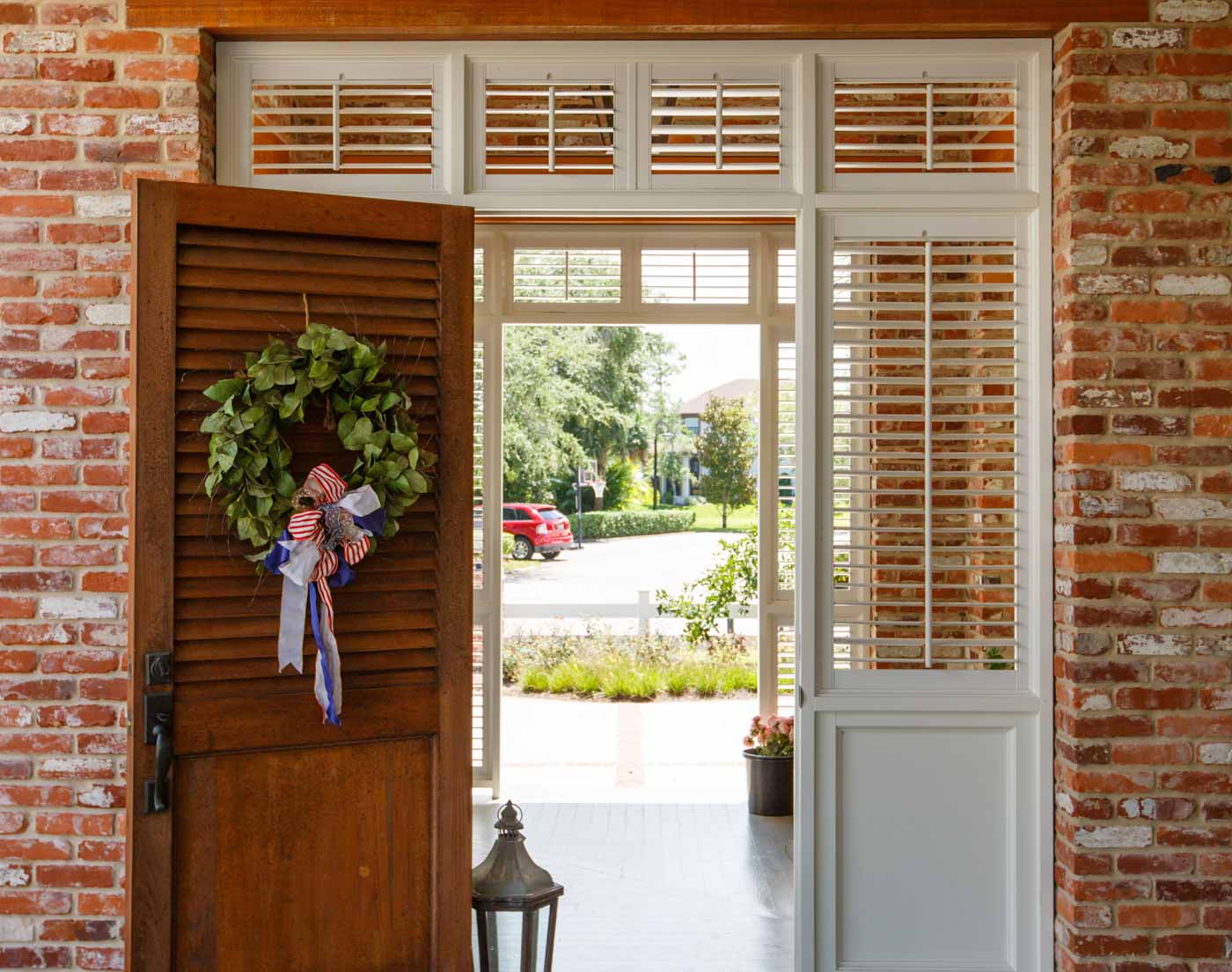Open front door with a wreath revealing a sunny suburban street.