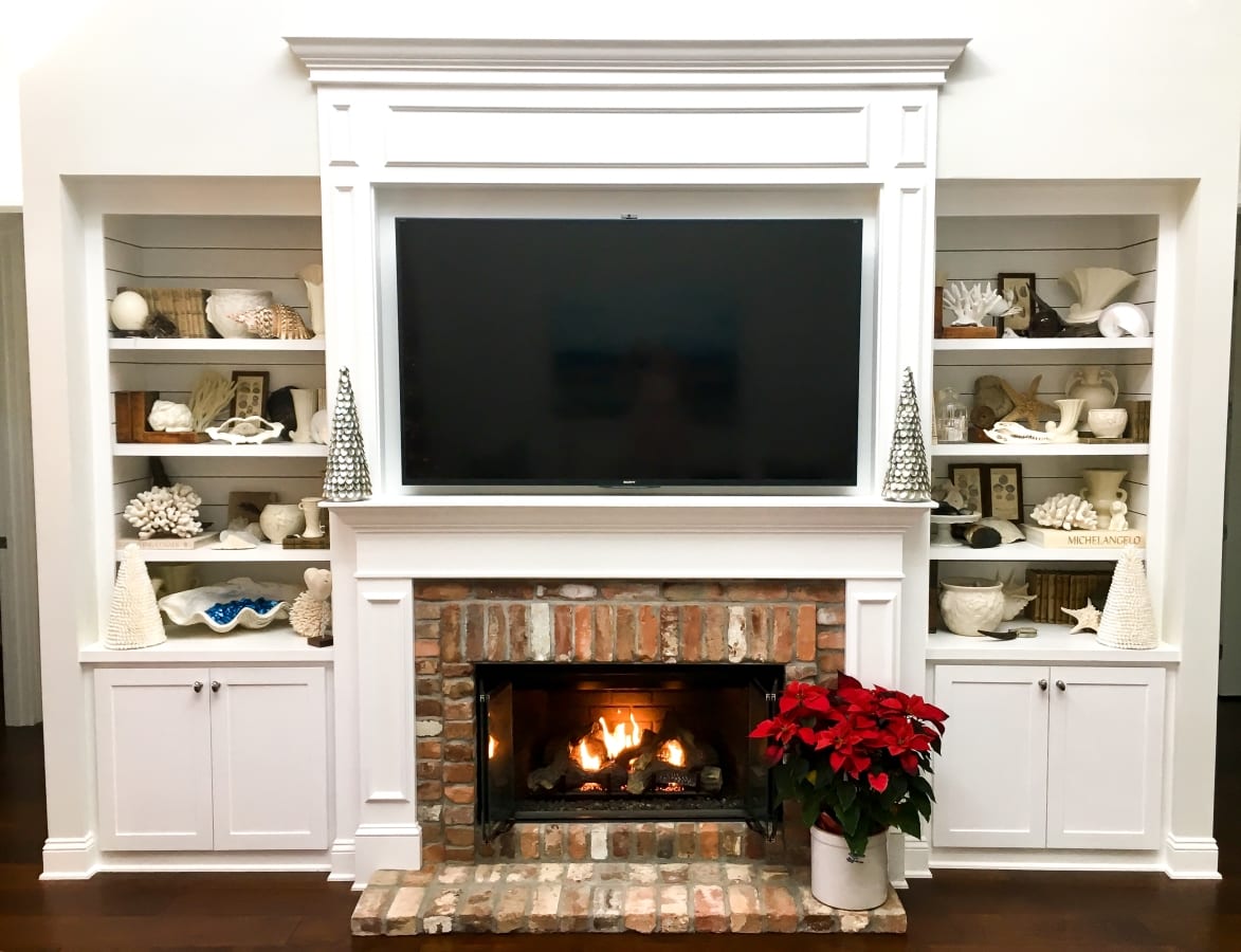 Cozy fireplace with TV and festive poinsettia beside it.