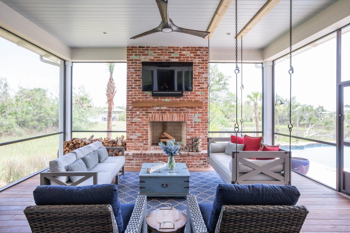 Modern living room with large windows, brick fireplace, and cozy seating.
