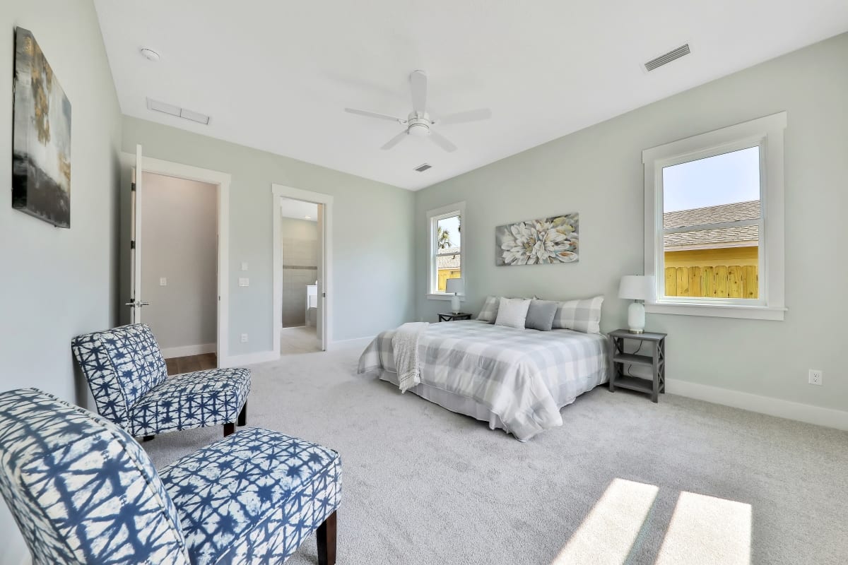 Bright bedroom with patterned chairs and neutral decor.