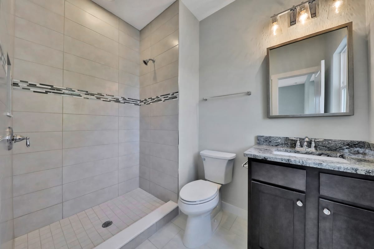 Modern bathroom with glass shower, toilet, and vanity.