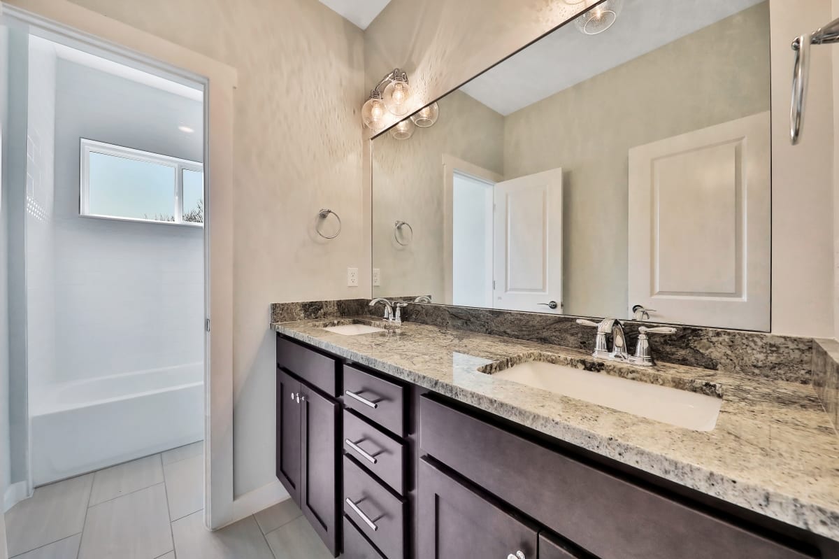 Modern bathroom with double sinks and granite countertops.