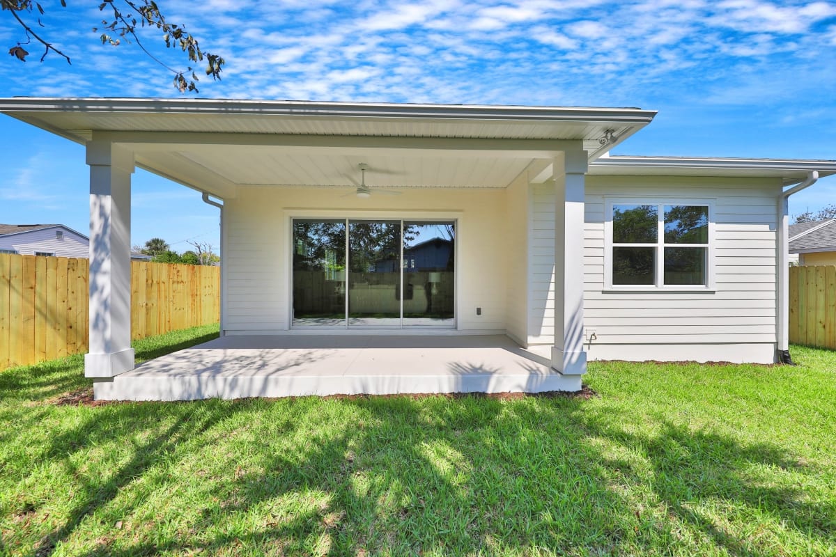 Back patio with sliding glass doors overlooking a green lawn under a blue sky.