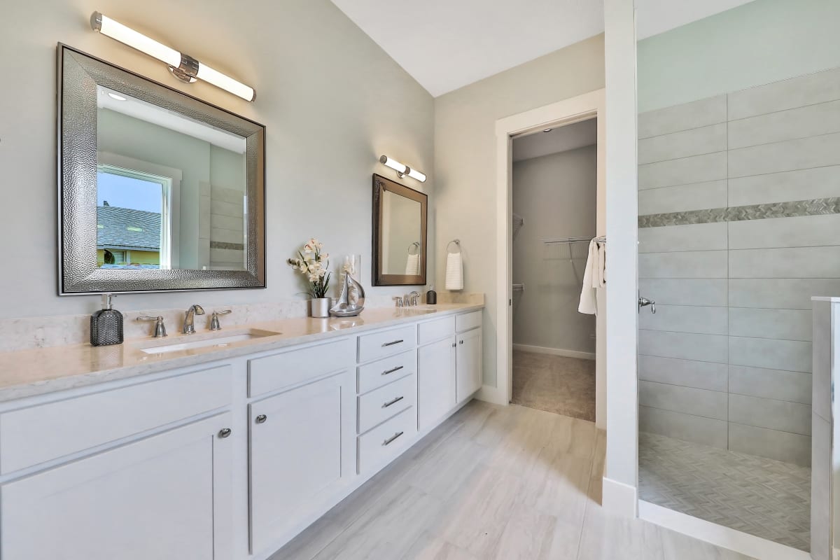 Bright modern bathroom with white cabinetry and glass shower.