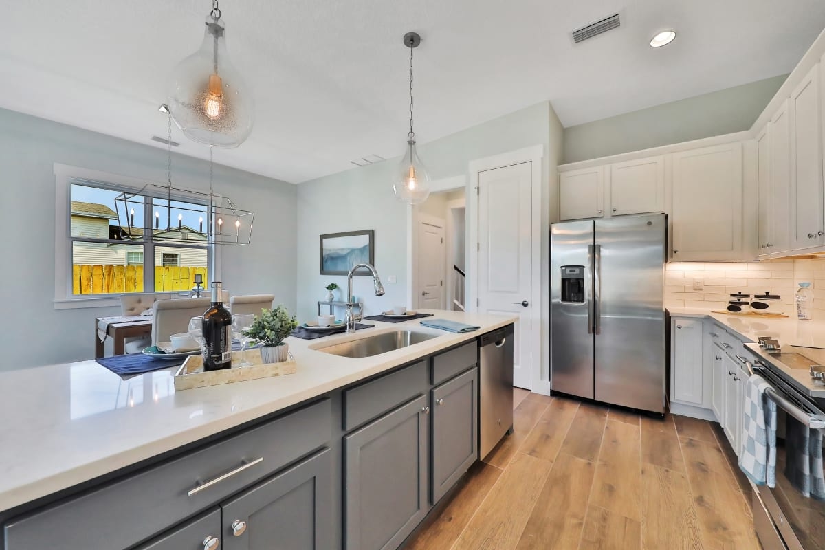 Modern kitchen with gray island, stainless steel appliances, and pendant lights.