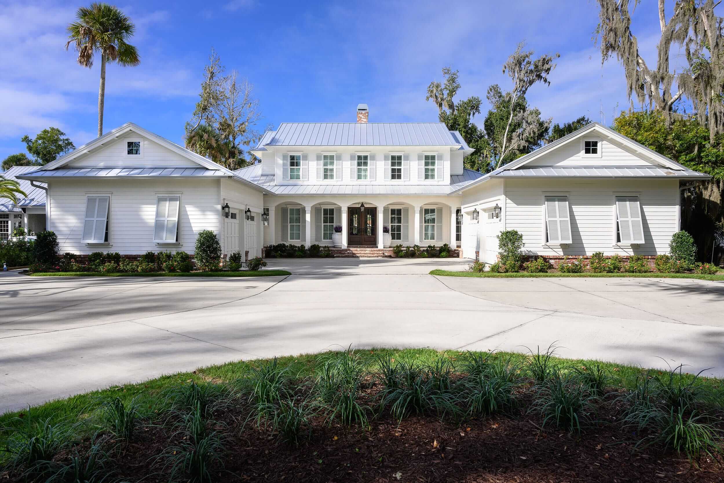 Elegant white mansion with a circular driveway and manicured landscaping.