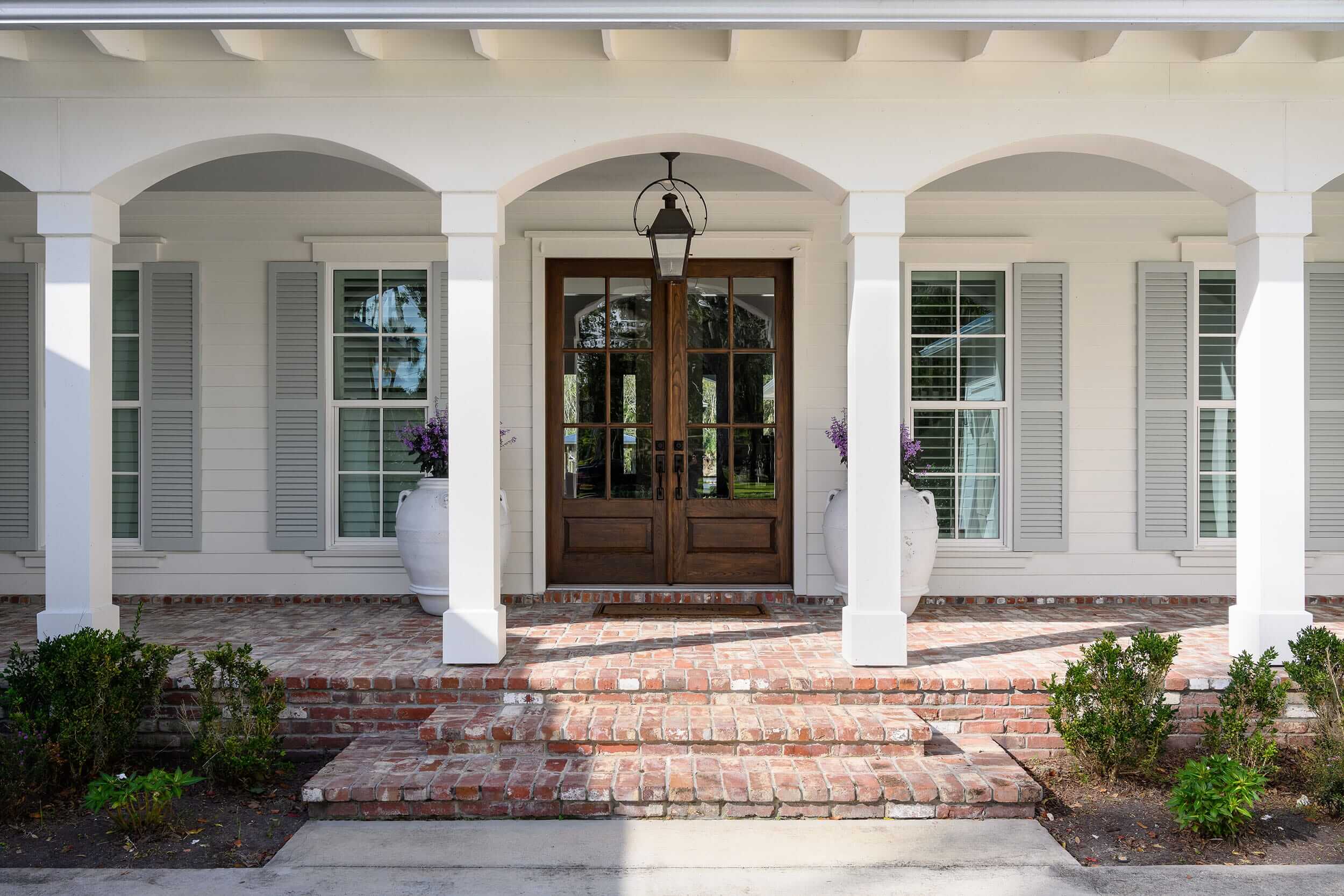 Elegant front porch with wooden double doors and brick steps.