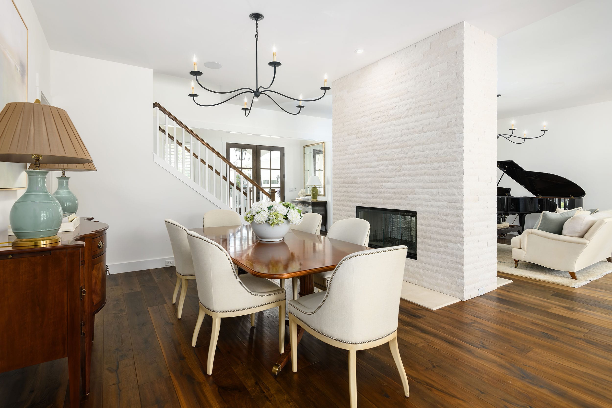 Modern dining area with wooden table, white chairs, and a brick fireplace.