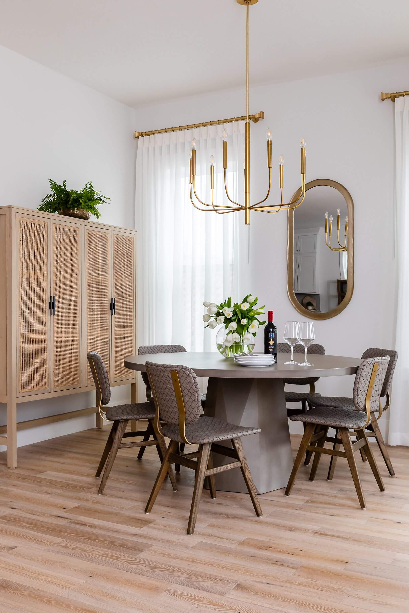 Elegant dining room with round table, wicker chairs, and golden chandelier.