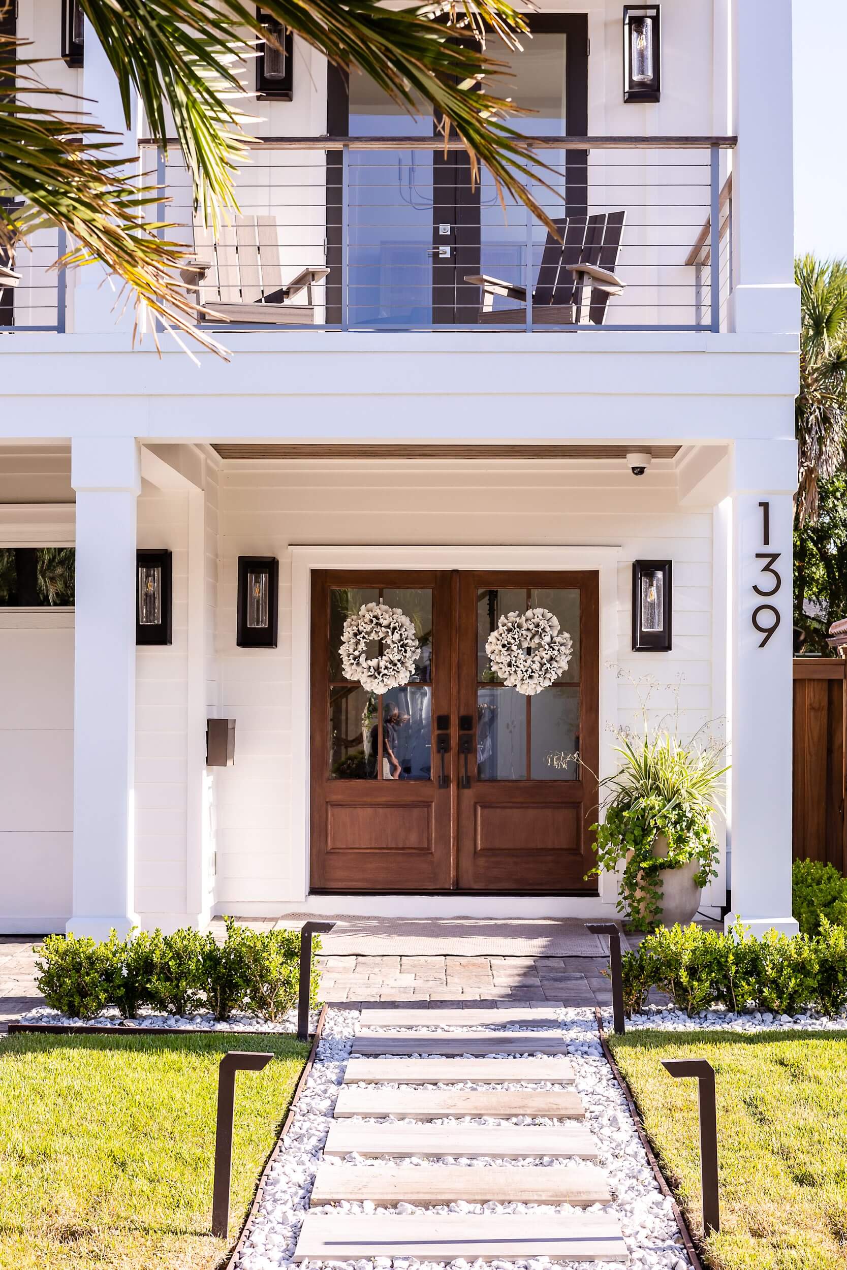 Elegant front entrance with double wooden doors and decorative wreaths.