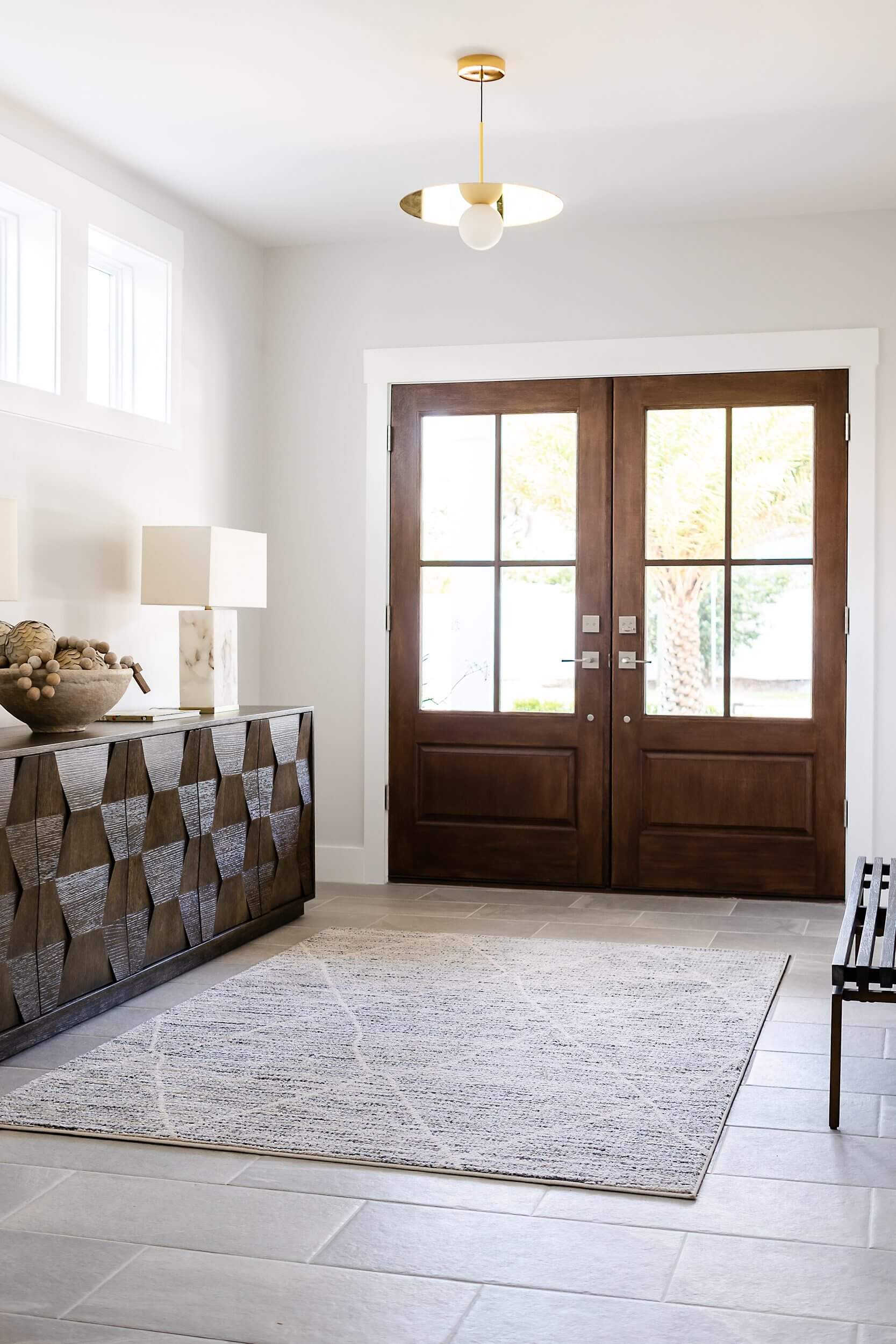 Elegant entryway with wooden double doors and geometric patterned sideboard.