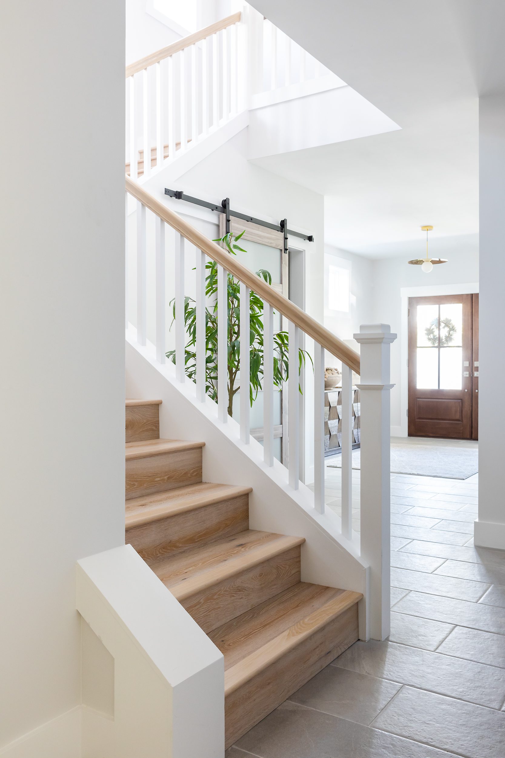 Bright modern staircase with wooden steps and white railings in a clean, airy home.