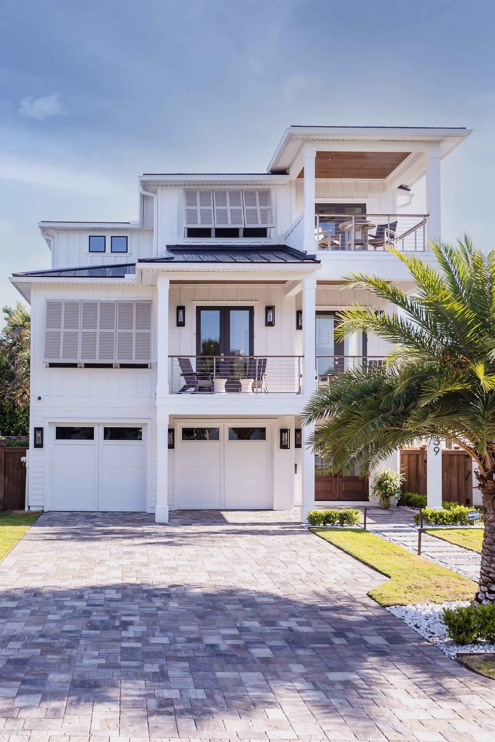 Modern white multi-story house with garage and balcony.